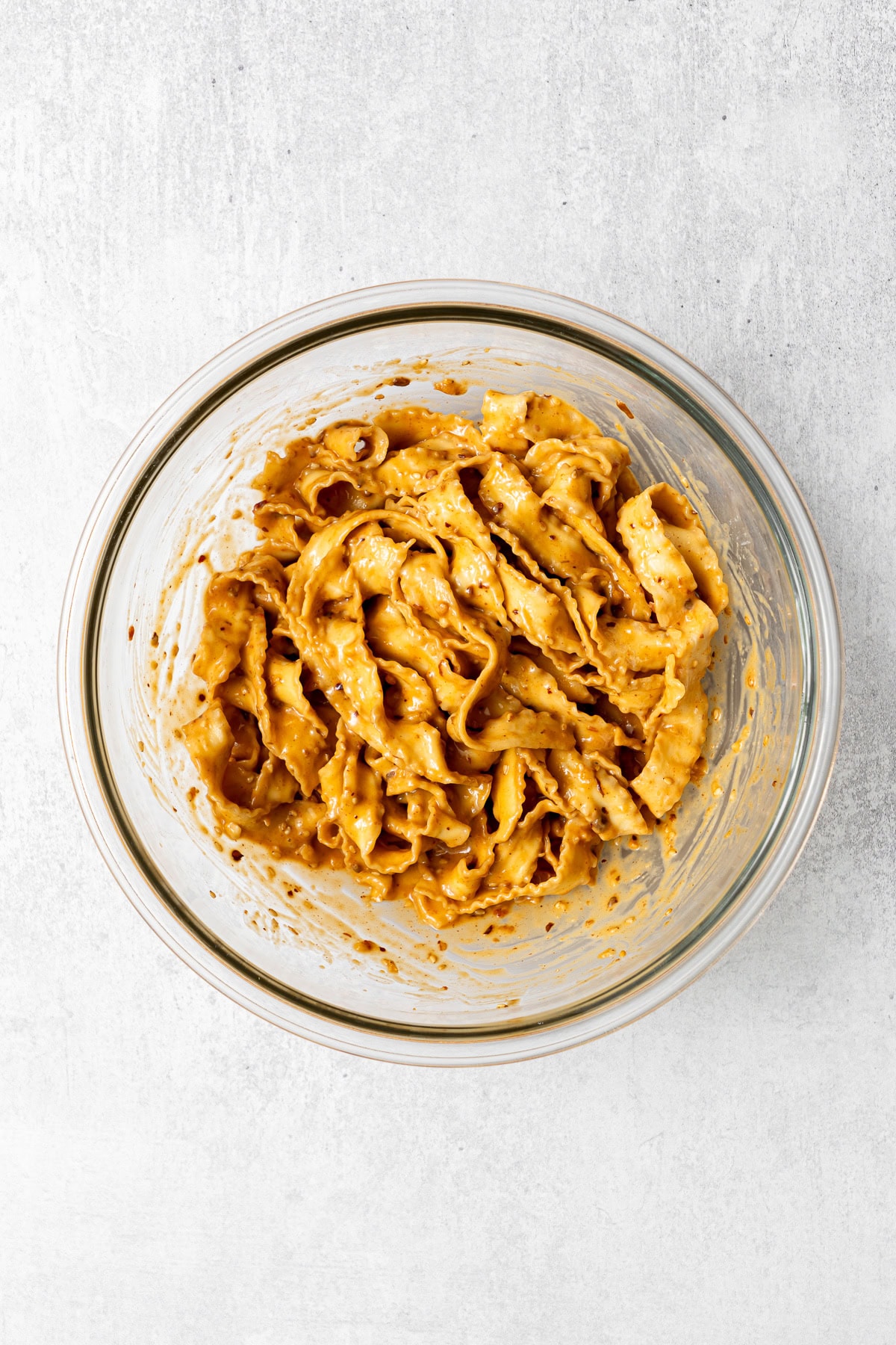 spicy peanut noodles in a large mixing bowl