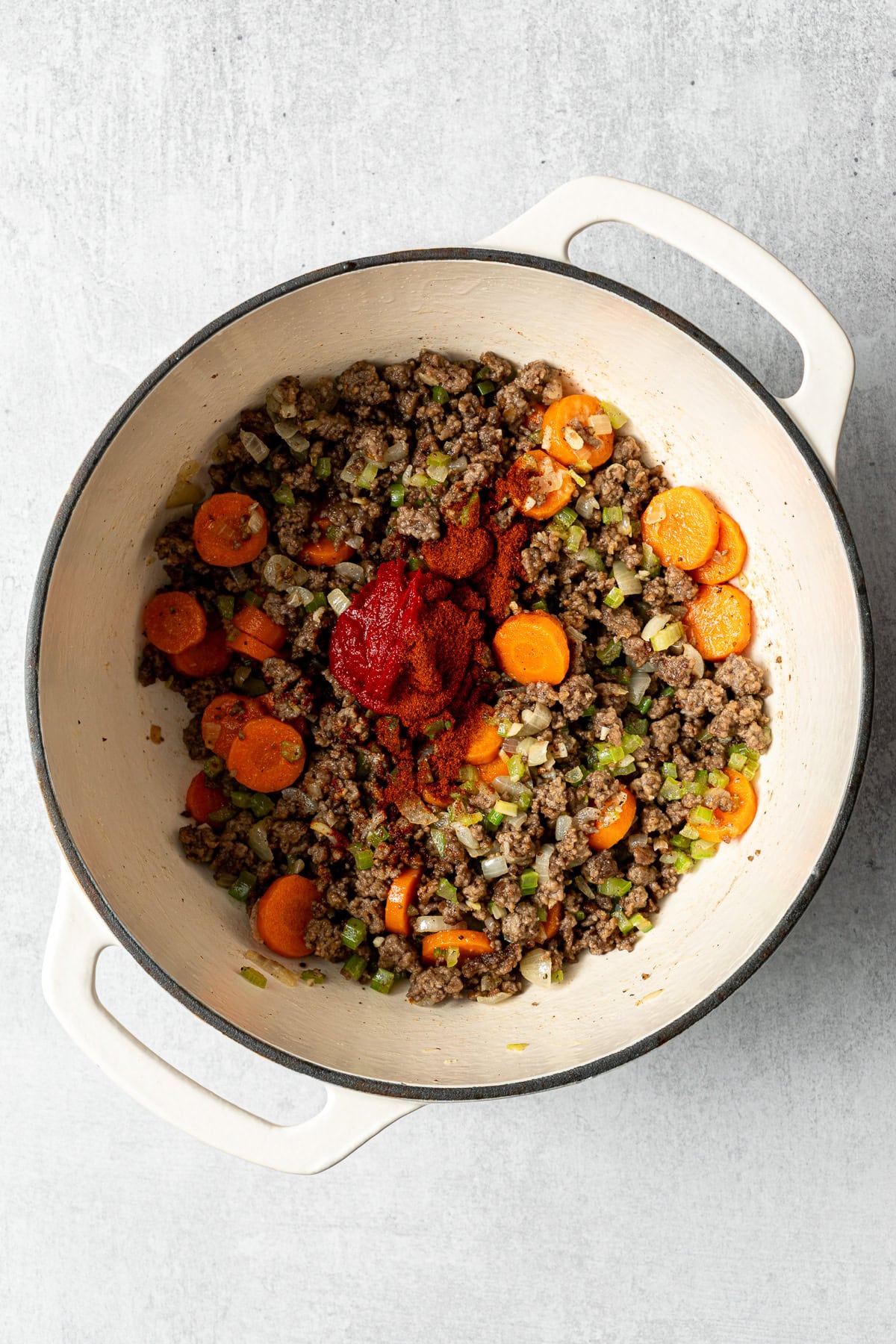 sautéed vegetables and ground beef with spices and tomato paste in a pot