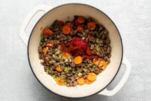 sautéed vegetables and ground beef with spices and tomato paste in a pot
