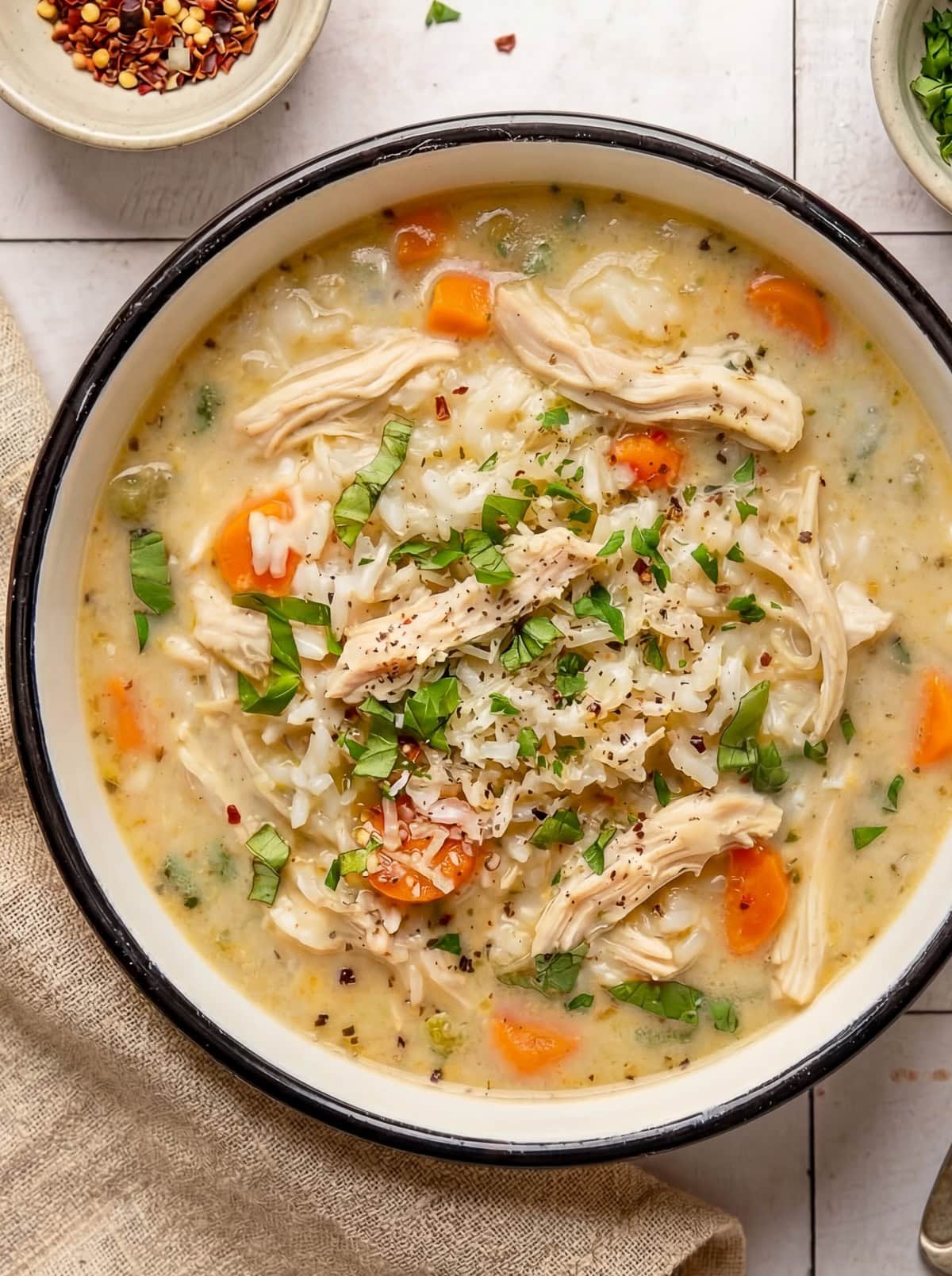 chicken and rice soup in a bowl garnished with chopped parsley and red pepper flakes