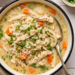 chicken and rice soup in a bowl garnished with chopped parsley and red pepper flakes