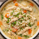 chicken and rice soup in a bowl garnished with chopped parsley and red pepper flakes