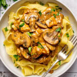 chicken stroganoff served over egg noodles in a bowl with a fork