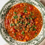 tomato lentil soup in a bowl garnished with chopped parsley