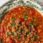 tomato lentil soup in a bowl garnished with chopped parsley