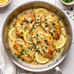 chicken piccata in a pan garnished with chopped parsley