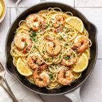 garlic butter shrimp pasta in a pan garnished with chopped parsley and red pepper flakes