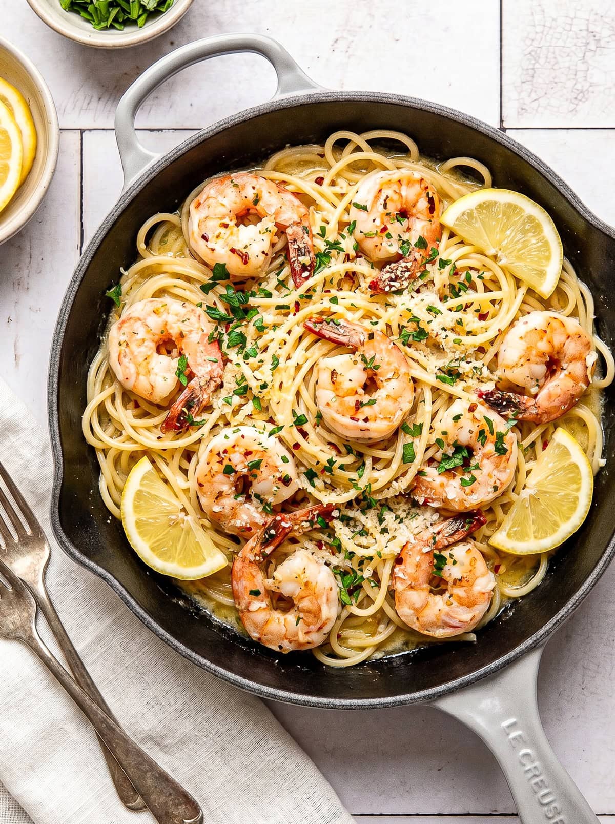 garlic butter shrimp pasta in a pan garnished with chopped parsley and red pepper flakes