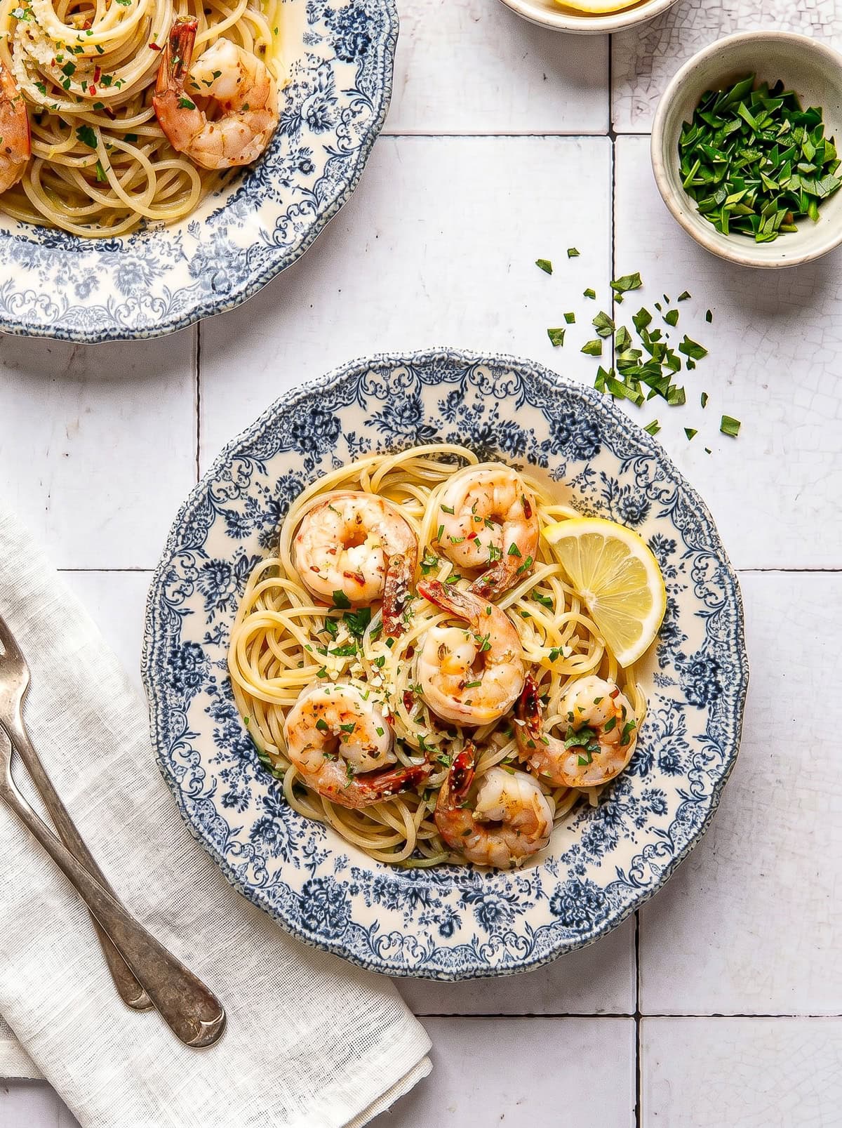 garlic butter shrimp pasta on a plate garnished with chopped parsley and red pepper flakes