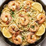 garlic butter shrimp pasta in a pan garnished with chopped parsley and red pepper flakes