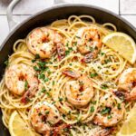 garlic butter shrimp pasta in a pan garnished with chopped parsley and red pepper flakes