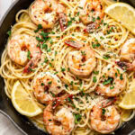 garlic butter shrimp pasta in a pan garnished with chopped parsley and red pepper flakes