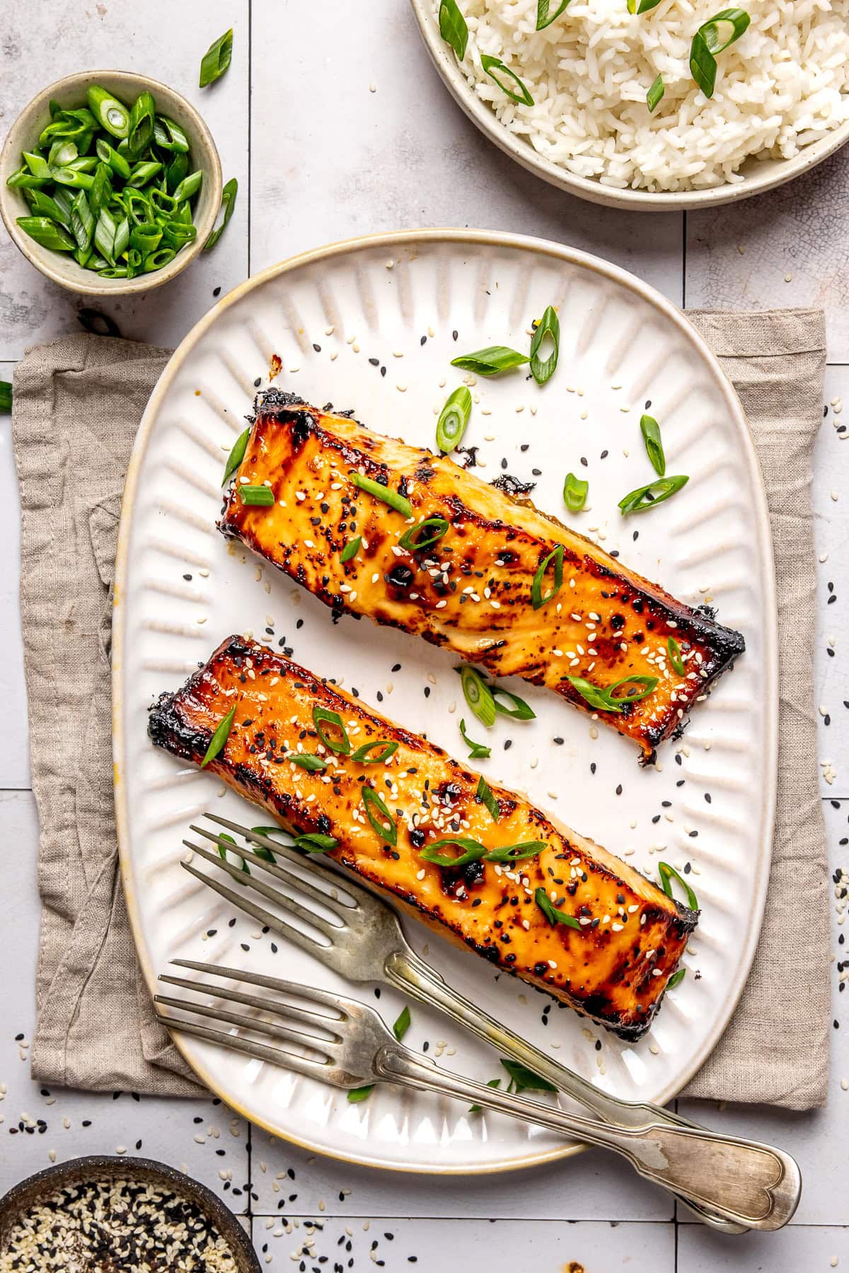 miso glazed salmon served on a long plate with two forks