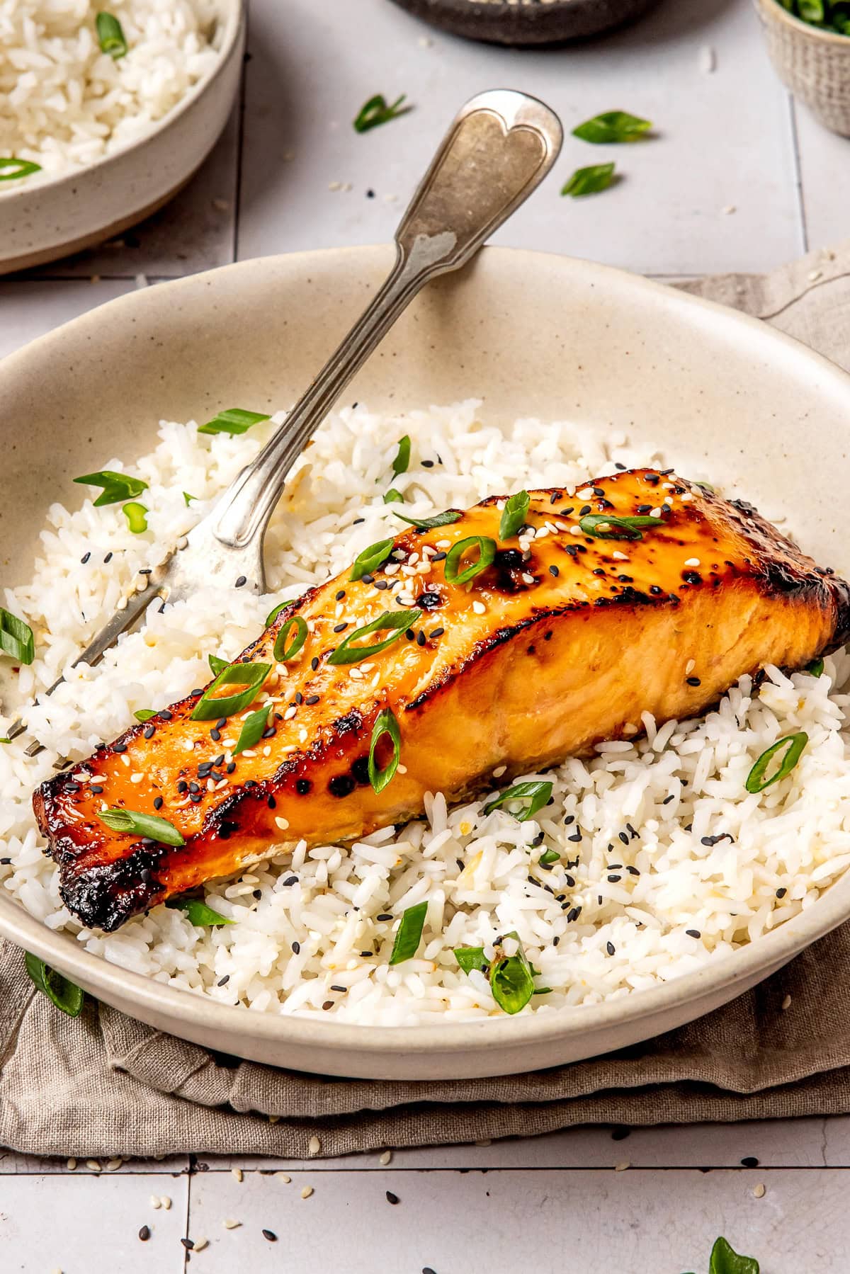 miso glazed salmon served over rice in a bowl with a fork