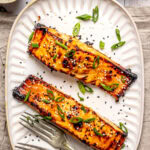miso glazed salmon served on a long plate with two forks