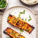 miso glazed salmon served on a long plate with two forks