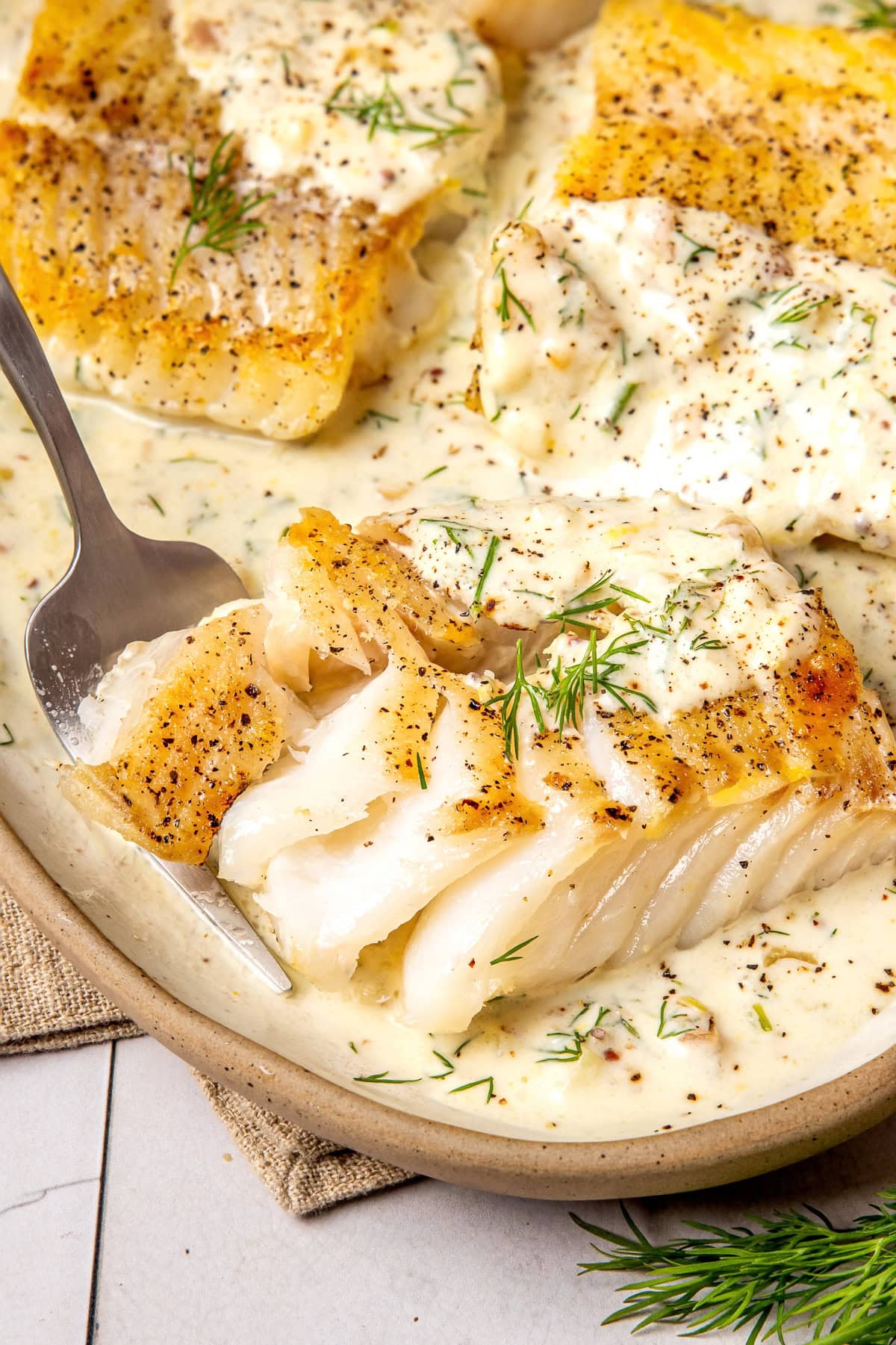 pan seared cod fillets with lemon dill cream sauce on an oval shaped plate
