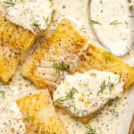 pan seared cod fillets with lemon dill cream sauce on an oval shaped plate