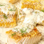 pan seared cod fillets with lemon dill cream sauce on an oval shaped plate