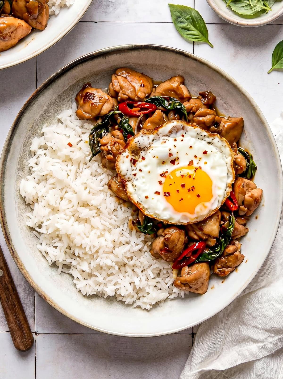 Thai basil chicken served in a bowl with white rice and a fried egg on top