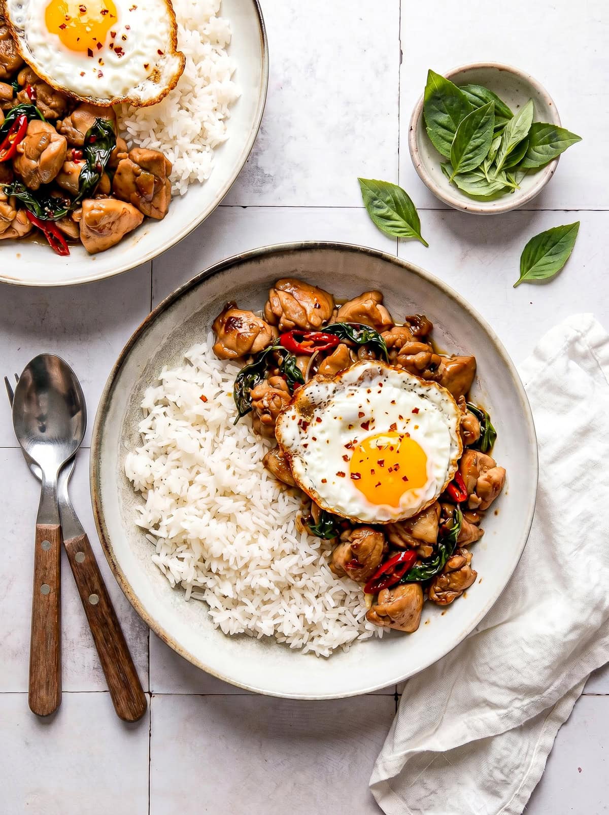 Thai basil chicken served in a bowl with white rice and a fried egg on top