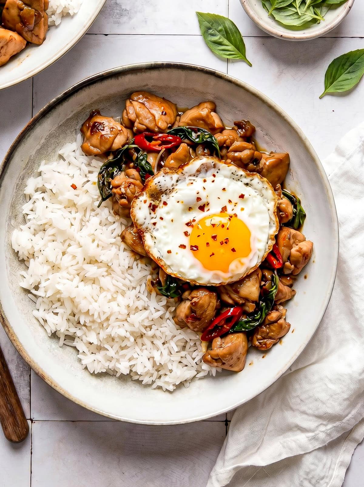 Thai basil chicken served in a bowl with white rice and a fried egg on top