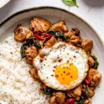 Thai basil chicken served in a bowl with white rice and a fried egg on top