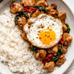 Thai basil chicken served in a bowl with white rice and a fried egg on top