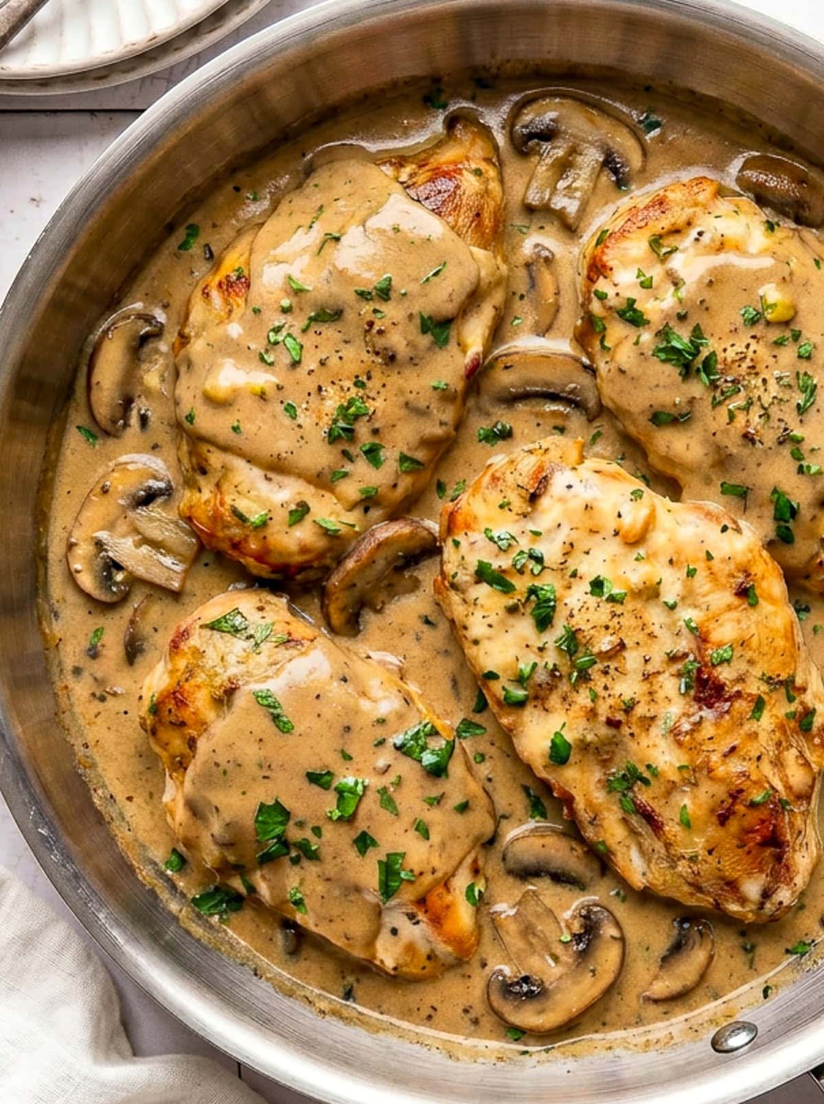 chicken marsala garnished with chopped parsley in a pan