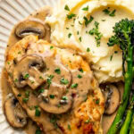 chicken marsala served with mashed potatoes and roasted broccolini on a plate garnished with chopped parsley