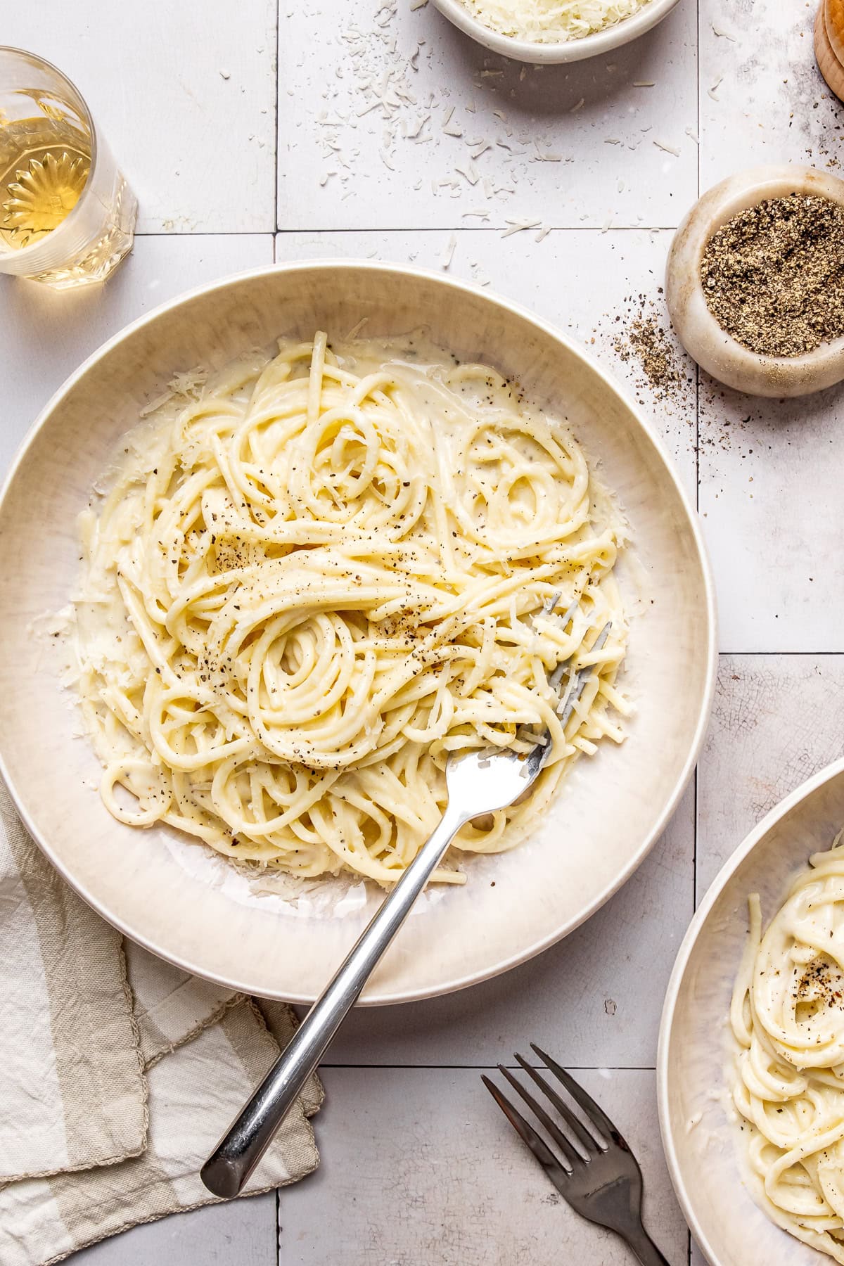 cacio e pepe garnished with black pepper and grated pecorino in a bowl with a fork