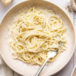 cacio e pepe garnished with black pepper and grated pecorino in a bowl with a fork