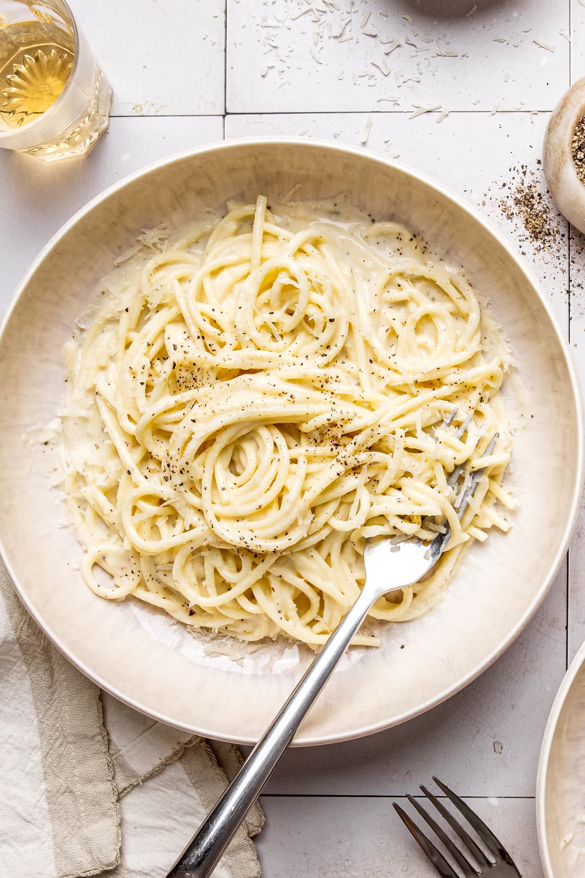 cacio e pepe garnished with black pepper and grated pecorino in a bowl with a fork