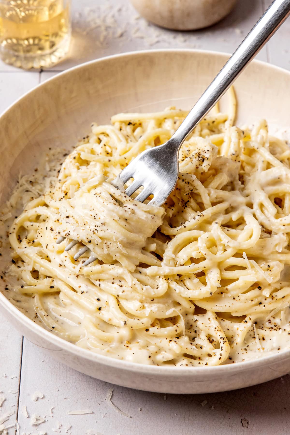 cacio e pepe garnished with black pepper and grated pecorino in a bowl with a fork