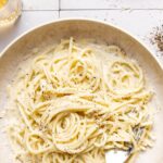 cacio e pepe garnished with black pepper and grated pecorino in a bowl with a fork