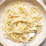 cacio e pepe garnished with black pepper and grated pecorino in a bowl with a fork