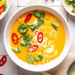 coconut curry pumpkin soup in a bowl garnished with red chili slices and cilantro