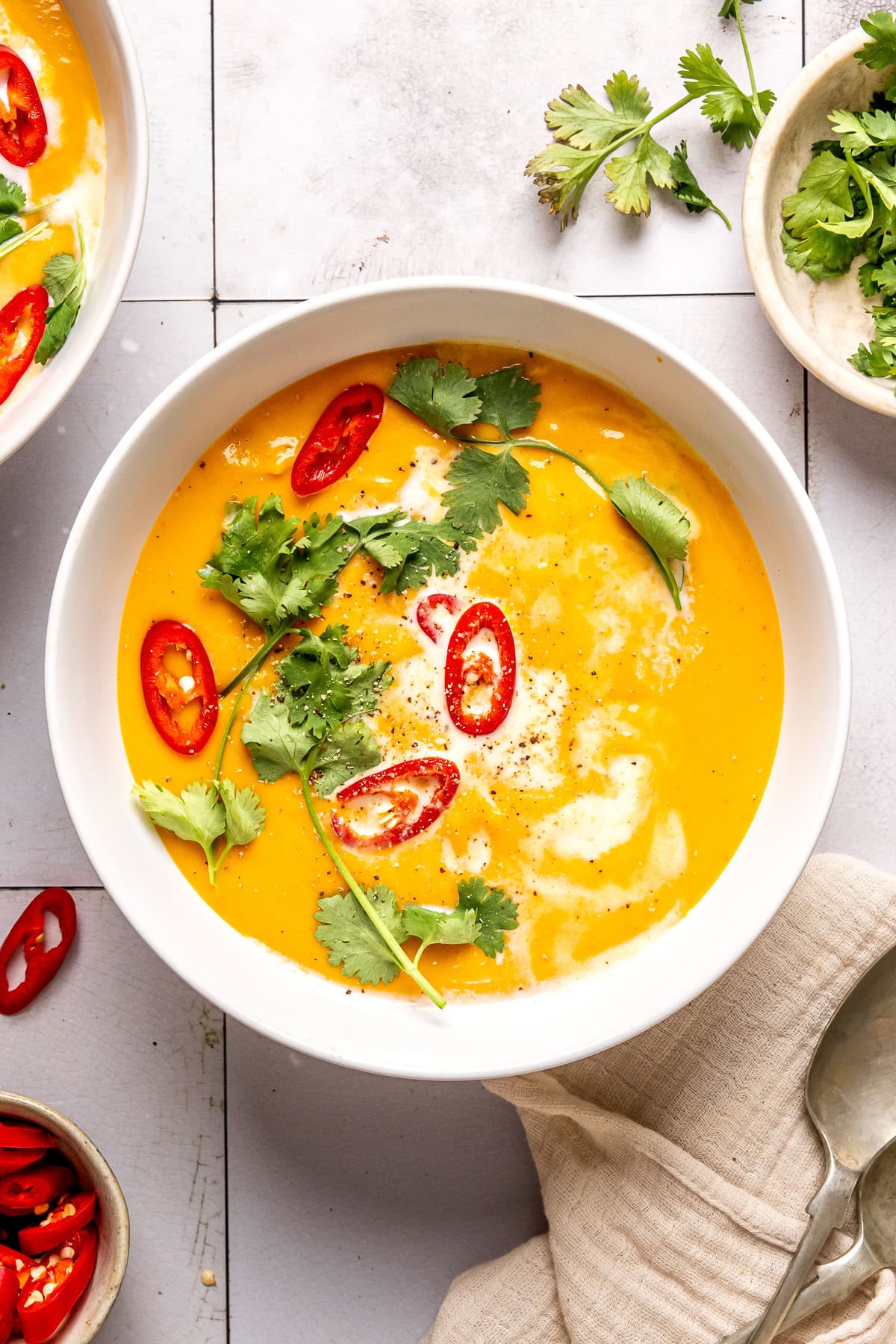 coconut curry pumpkin soup in a bowl garnished with red chili slices and cilantro
