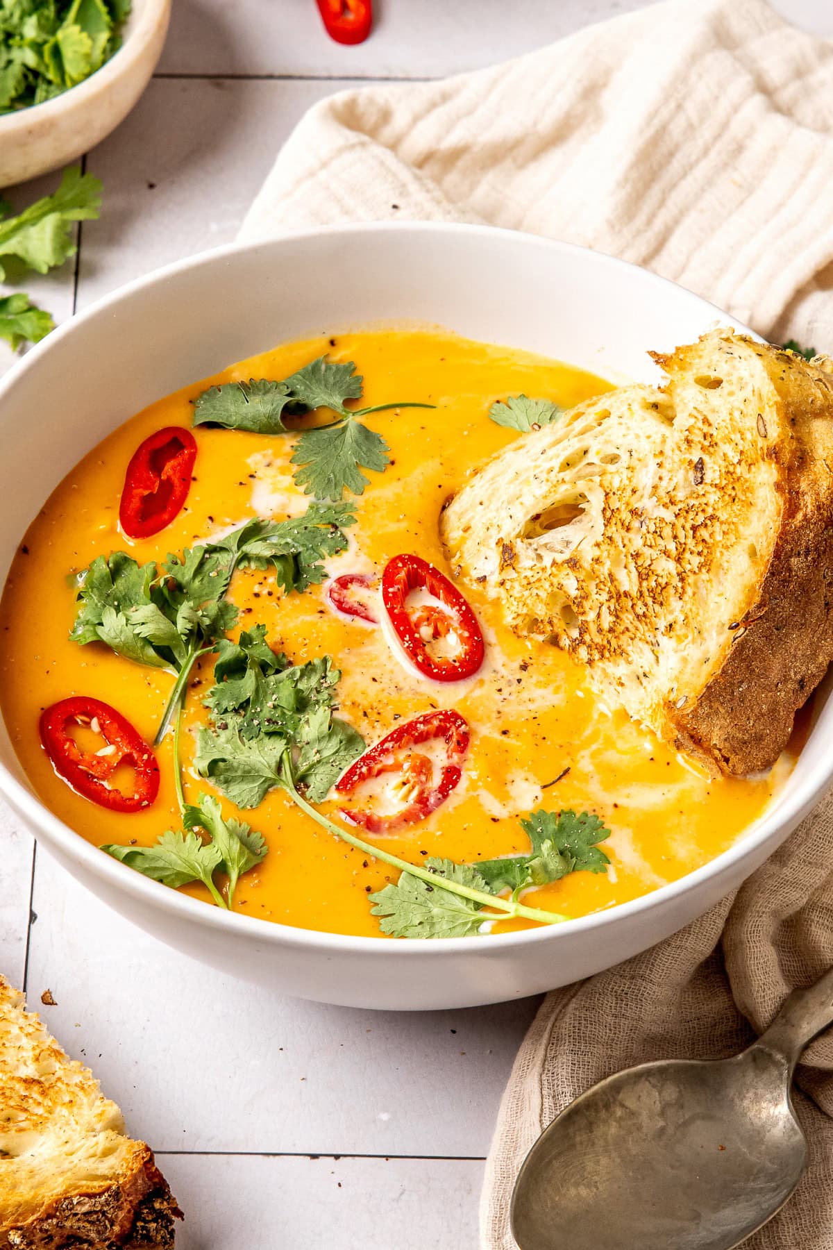 coconut curry pumpkin soup in a bowl garnished with red chili slices and cilantro