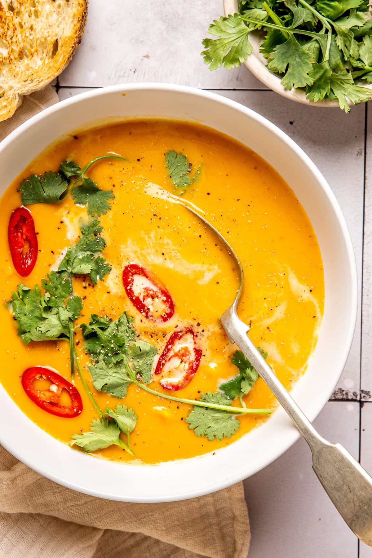 coconut curry pumpkin soup in a bowl garnished with red chili slices and cilantro