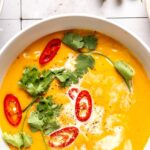 coconut curry pumpkin soup in a bowl garnished with red chili slices and cilantro
