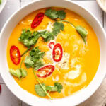 coconut curry pumpkin soup in a bowl garnished with red chili slices and cilantro
