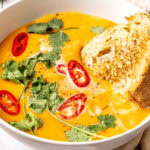 coconut curry pumpkin soup in a bowl garnished with red chili slices and cilantro